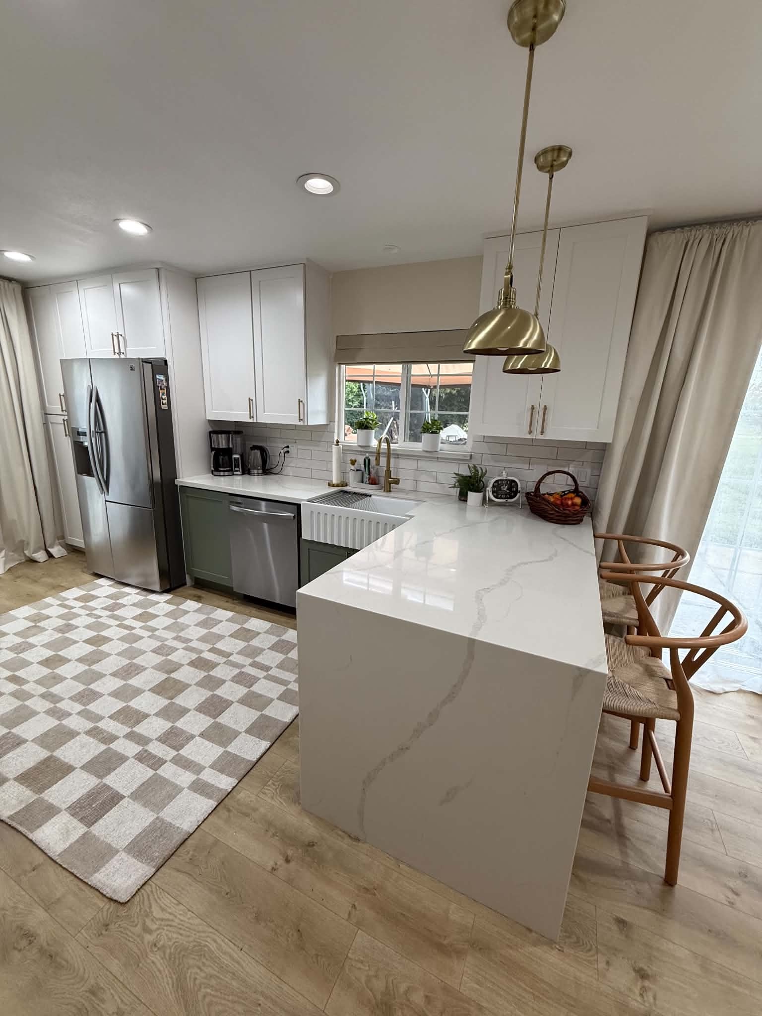 White and sage custom kitchen with waterfall peninsula and brass pendant lights