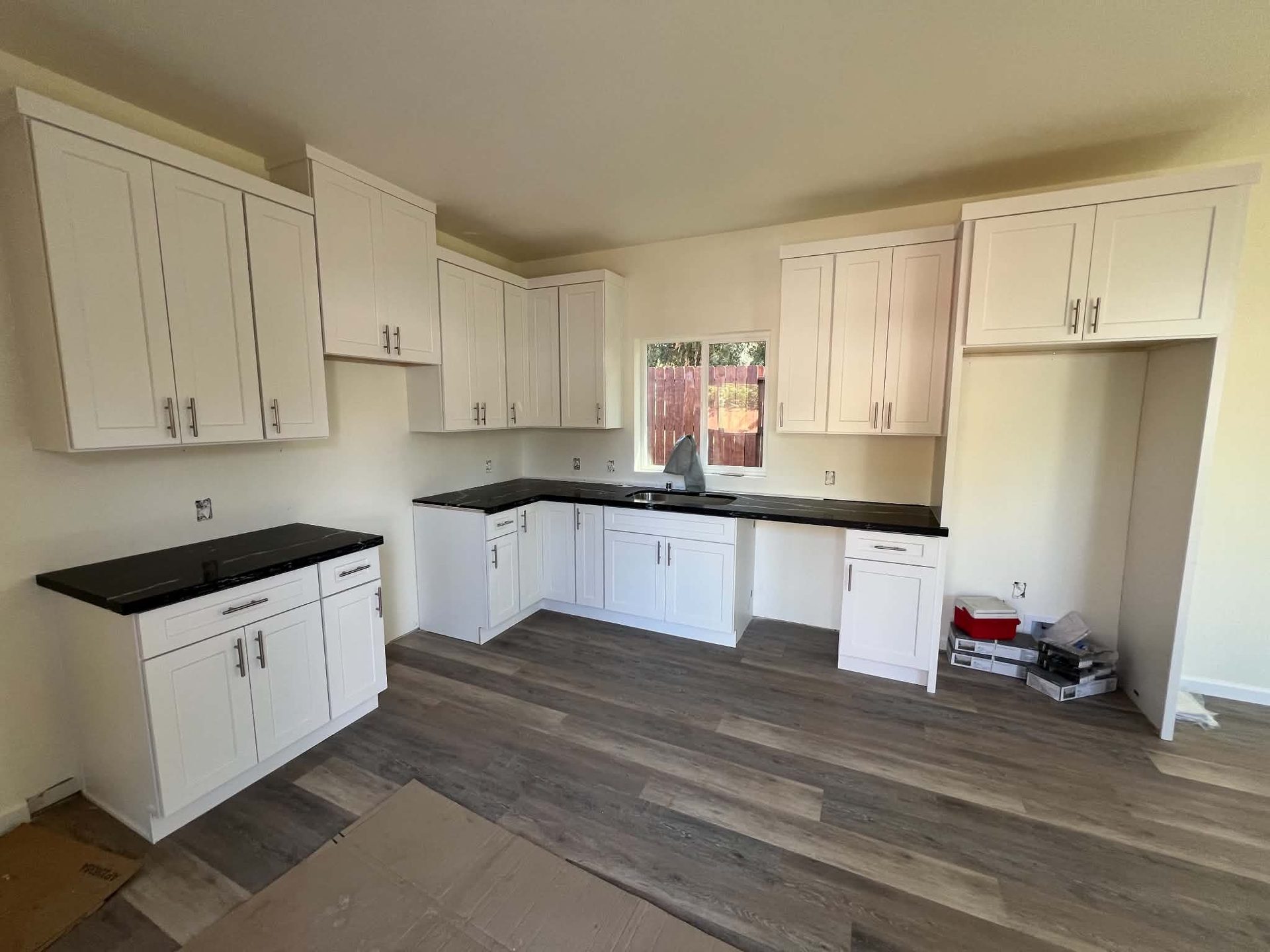 Kitchen remodel in progress with white shaker cabinets and black granite